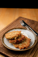 Crunchy and golden potato fritters ? rustic vegetarian snack with sour cream, appetising close up