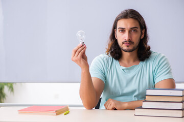 Young male student holding lamp in brainstorming concept