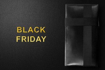 Gift box with black ribbon and Black Friday text on a black background