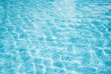 Blue swimming pool water with sun reflections.