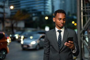 African businessman outdoors at night using mobile phone