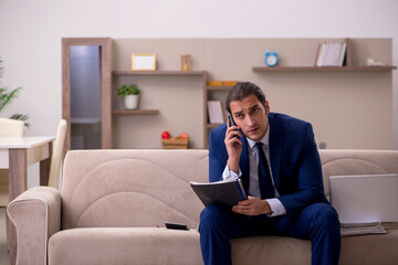 Fototapeta premium Young male employee working from home in pandemic concept