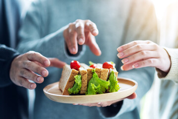 Group of people grabbing a piece of whole wheat sandwich in wooden plate to eat