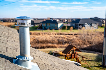 side view of a Galvanized metal chimney exhaust on  asphalt roof with a rain cap
