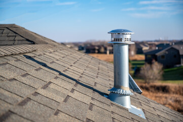side view of a Galvanized metal chimney exhaust on  asphalt roof with a rain cap - obrazy, fototapety, plakaty