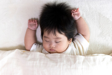布団をかぶって寝ている赤ちゃんの顔、0歳、生後4か月、女の子