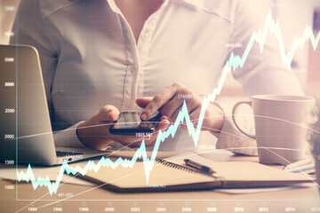 Double exposure of forex chart sketch hologram and woman holding and using a mobile device. Financial market concept.