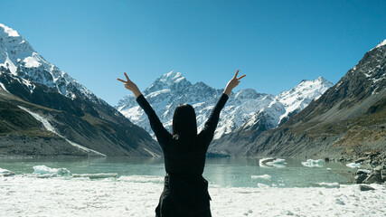 A woman stand alone Victory pose to Mt. cook peak, Tasman lake, in Newzealand