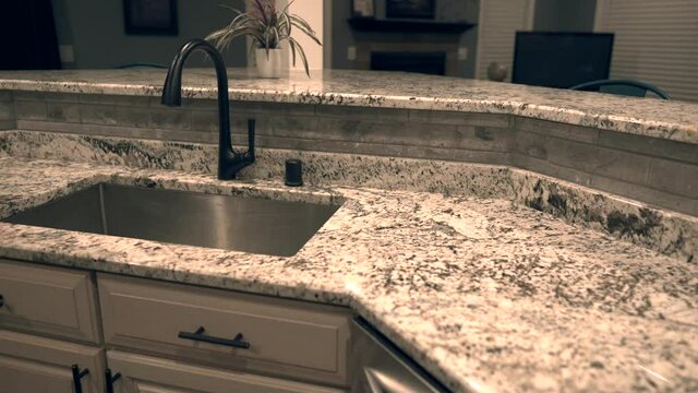 Beautiful kitchen granite countertops in gray and white colors on white contemporary kitchen cabinets and gray backsplash