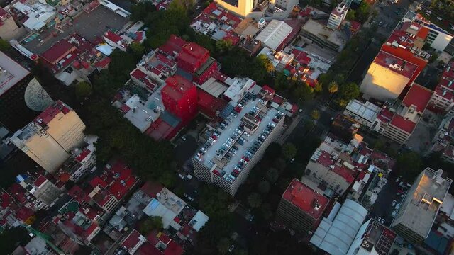 Aerial view over the streets of Mexico city, revealing a skyscraper, at the Glorieta de los Insurgentes, during sunset - tilt up, drone shot