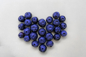 Blueberries in the shape of heart on a yellow background.