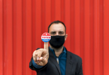 Man holding a sticker with the American flag colors with 'I voted today' written on it