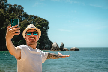 Caucasian man taking a selfie with smartphone in Split Apple Rock, Abel Tasman National Park, New...