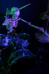 High view bony man lit by purple light with green highlights drumming