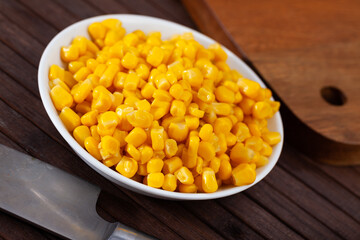 Cooked sweet corn kernels in bowl on wooden table