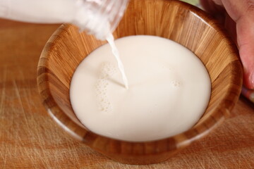 Pouring milk into wooden bowl