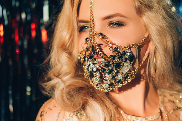 Quarantine carnival. Pandemic jewelry. Glamour festive look. Happy blonde woman in sparkling gold...