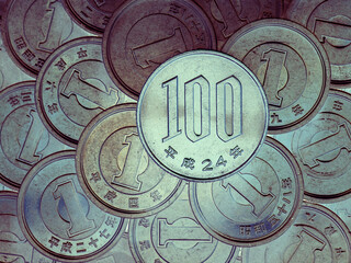 100 yen lies on a pyramid of Japanese 1 yen coins. View from above. Inverted colors. An unusual catchy illustration on a financial theme. News about economy of Japan. Deposits and interest. Macro