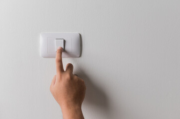 Fototapeta Earth Hour, Close up male hand turn off the light to saving electrical energy. Finger pushing light switch turn on or off. White switch with copy space at home. obraz