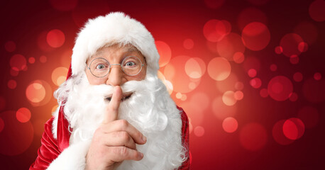 Portrait of Santa Claus showing silence gesture on color background