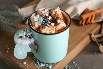 Cup of hot cacao drink with marshmallows and Christmas decorations on table