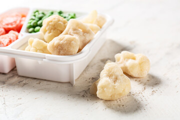Divided box with different frozen vegetables on white background