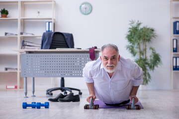 Aged male employee doing physical exercises during break