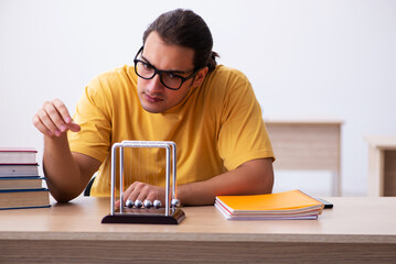 Young male student physics preparing for exams in the classroom
