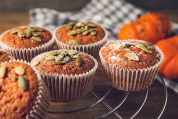 Cooling rack with tasty pumpkin muffins on table, closeup