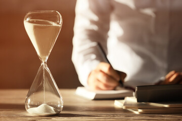 Hourglass on table of businesswoman in office
