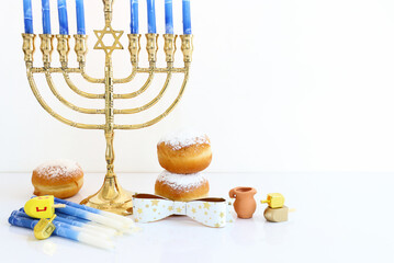 Image of jewish holiday Hanukkah with menorah (traditional Candelabra), donut and wooden dreidel (spinning top)