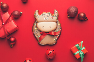 Tasty cookie in shape of bull and Christmas decor on color background