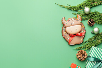 Tasty cookie in shape of bull and Christmas decor on color background