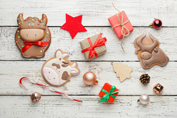 Tasty cookies in shape of bull and Christmas decor on wooden background