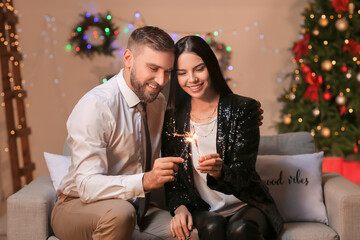 Young couple with sparklers celebrating Christmas at home