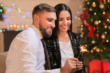 Young couple with sparklers celebrating Christmas at home