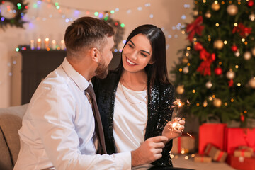 Young couple with sparklers celebrating Christmas at home