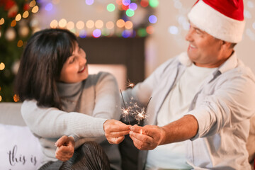 Mature couple with sparklers celebrating Christmas at home