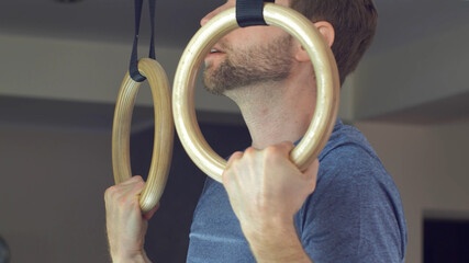 Man Works Out Pull-ups on Gymnastics Rings at Home 