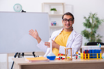 Young male chemist teacher in front of white board