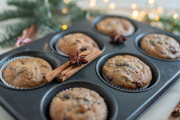 Fresh homemade gingerbread muffins in baking form on wooden table with Christmas decoration