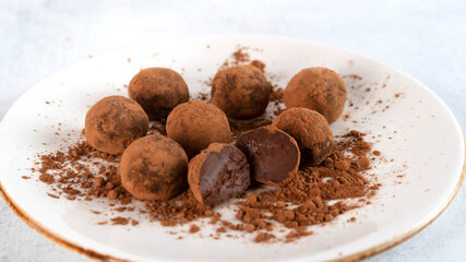 Homemade healthy tasty chocolate truffles lie on a plate. One truffle is cut in half. Delicate cream inside. Selective focus. Side view. Horizontal orientation.