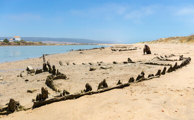 On the beach on the Spanish Atlantic coast, numerous old rotted fishing boats lie in the sand on...