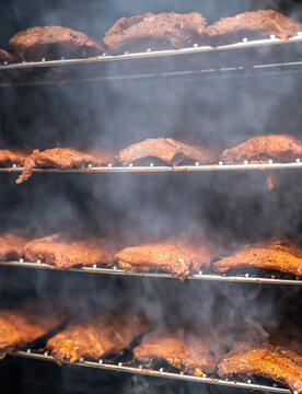 smoke rising around a slow cooked beef brisket on a smoker barbecue grilling concept