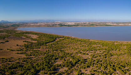 Fototapeta na wymiar The western part of the La Mata lagoon north of the Spanish city of Torrevieja. The city of Montesinos can be seen in the background. Mountains are on the horizon.