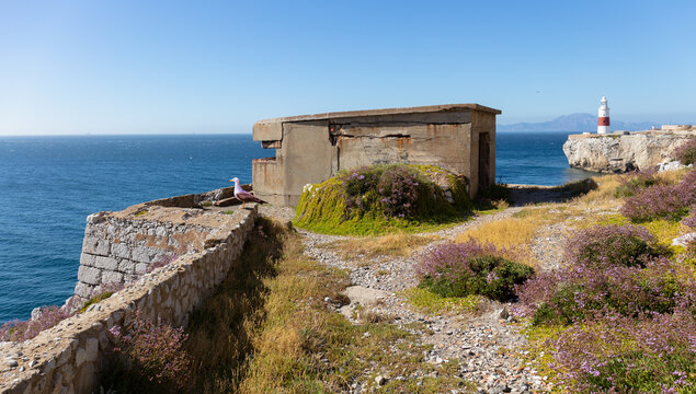A historic military rifle range on the southern tip of Gibraltar in summer. In the background is the red and white lighthouse and on the horizon the Spanish coast.