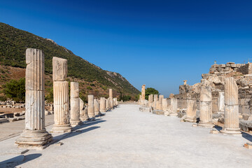 Marble ancient columns along the road in ruins of antique Ephesus city on a sunny day, Turkey	