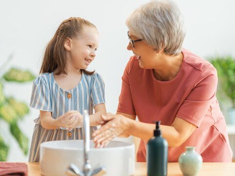 girl and her grandmother are washing hands