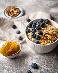 Healthy breakfast bowl: oatmeal with blueberries, nuts and honeycomb piece. Oat flakes with berries and walnuts. 