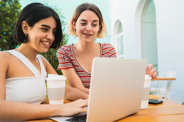 Two young friends using a laptop at coffee shop.